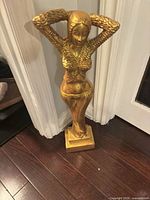 Full view of gold painted wood female figure sculpture on base