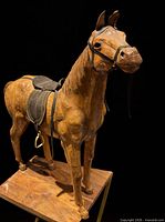 Full front-angle view of wooden horse sculpture showing saddle and bridle