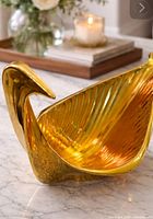 Front three-quarter view of gold bird bowl on marble surface
