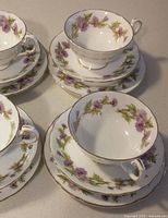 Group of teacups, saucers and plates showing pattern and gold trim