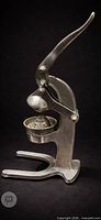 Front view of cast metal citrus press showing lever and strainer cup