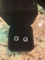 Front view of both square blue sapphire stud earrings in box