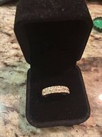 Band ring seated in black velvet box, showing top view of stones