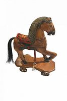 Side view of wooden pull toy horse showing saddle, mane, wheels, and pull string