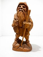 front view of carved wooden wanderer figure showing beard, staff, cloak
