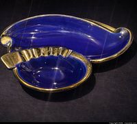 Full view of ceramic ashtray showing crescent tray and round fluted bowl, cobalt blue glaze with gold edging