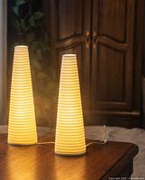 Two illuminated ribbed porcelain cone lamps on table
