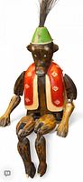 Full view of carved wooden monkey toy seated, showing vest and hat