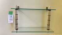 Full view of two-tier brass and glass wall shelf mounted on wall