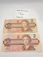 Both $2 banknotes front side, pencil marking visible on top note