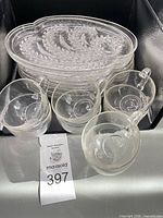 Stack of ornate clear snack plates and several cups showing design and transparency