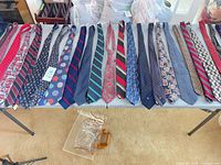 All 25 ties laid flat on table showing variety of colors and patterns