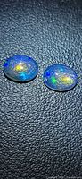 Two oval crystal opals showing play of colour on black background