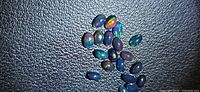 Group of small oval black opals on textured surface