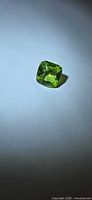 Loose vivid green cushion-cut peridot on white background