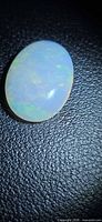 Front view of oval cabochon white opal on dark background