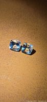 Pair of cushion-cut blue aquamarines on brown background