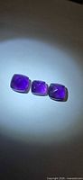 Three deep purple Sugarloaf cut amethysts on neutral background