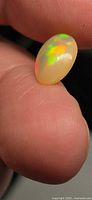 Opal on fingertip showing green and red flashes