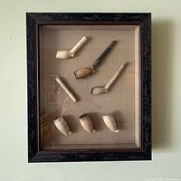 Frontal view of framed display showing all nine pipe fragments and frame style