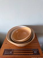 Three nested ceramic bowls on table beside ruler