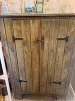 Cabinet front closed showing green plank doors and metal hardware