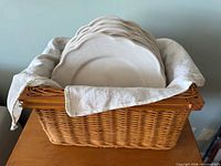 Plates stacked in wicker basket with cloth liner