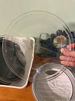 Clear glass pie dish held up, metal pie dish beneath