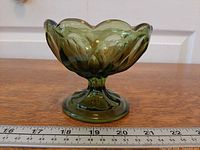 Side view of green pressed glass pedestal compote showing pattern and size reference