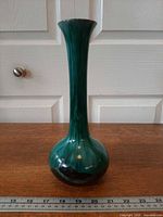 Full frontal view of tall blue-green glaze vase beside ruler