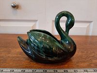 Left side profile of swan planter showing glossy green-black drip glaze and overall form with ruler for scale