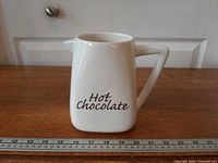 Front view of white ceramic Bonjour hot chocolate pitcher with "Hot Chocolate" text