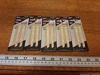 Five sealed packs of Briggs & Stratton blades with ruler for scale