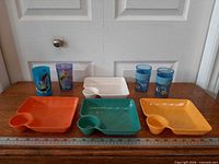 Front view of four cups and four platters showing characters and colours