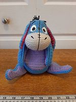 Front view of crochet Eeyore showing colors, facial features and ruler for scale