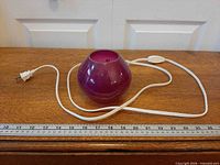 Entire lamp with white cord, plug and inline switch positioned beside ruler