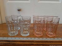 Eight faceted glasses lined on table with ruler for scale