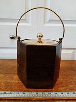 Front view showing octagonal faux wood exterior, brass-tone handle and lid