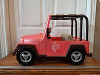 Left side view of pink 4x4 toy vehicle showing door decal, wheels, roll cage