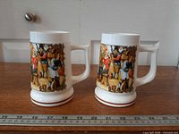 two milk glass steins side by side with ruler for scale