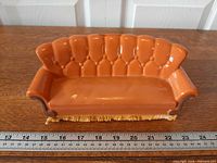 Front view of ceramic Friends couch coin bank with ruler for scale