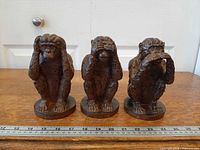 Front view of all three resin monkey figurines beside ruler