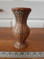 Front view of hourglass wicker wrapped terracotta vase with ruler for scale