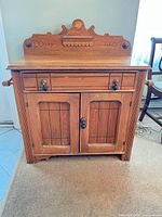 Front view of oak sideboard showing drawer, doors, hardware and towel bars