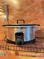 Front view of Hamilton Beach stainless slow cooker showing brand badge and control dial