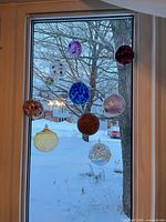Cluster of 10 hanging glass spheres in window, shows overall assortment