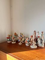 Full lot of assorted Hummel and other porcelain figurines on dresser