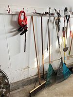 Overall view of hanging tools including hedge trimmer, rake, broom, cultivator and leaf rakes
