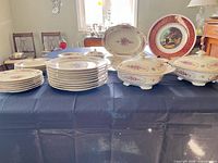 Multiple stacks of plates, footed bowls, covered tureens, platter and charger on table