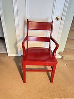Front view of red ladder-back armchair showing seat, arms and legs
